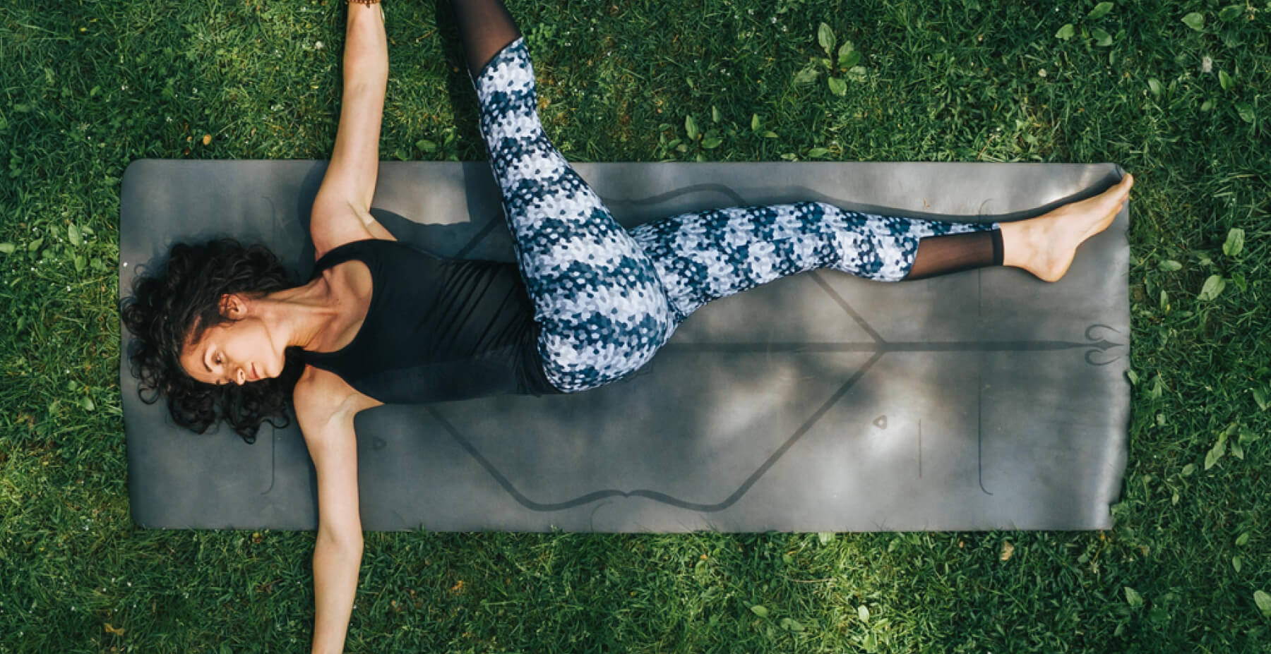 A woman practicing yoga, performing a graceful pose on a mat in a serene environment.