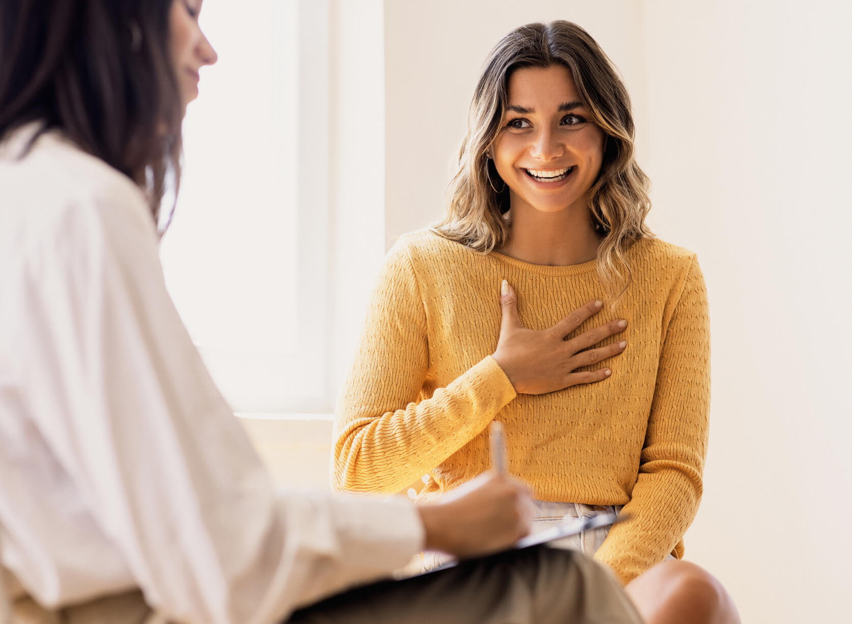 Two women engaged in a lively conversation, sitting together and sharing a moment of connection and laughter.